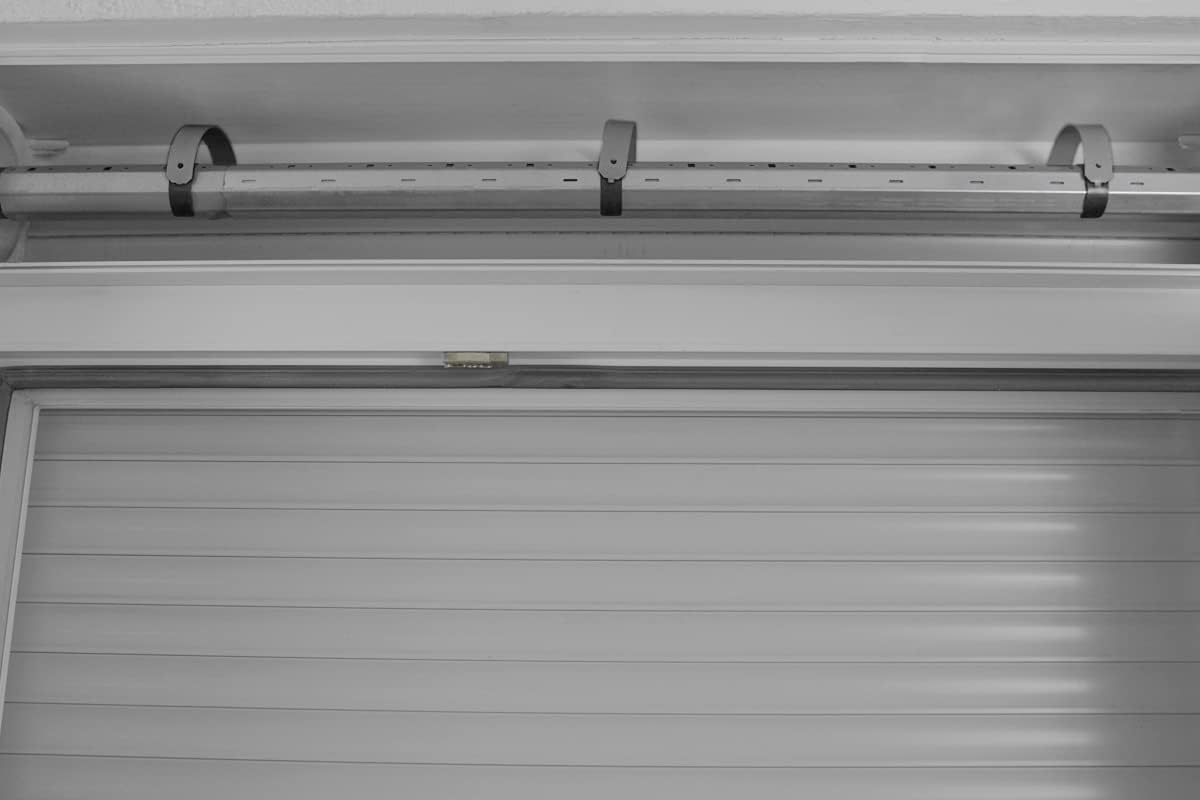 Close-up of a hand clamping a Schellenberg hanging bracket onto a roller shutter shaft