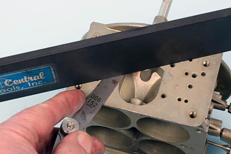 Using a feeler gauge to measure clearance on a carburetor component
