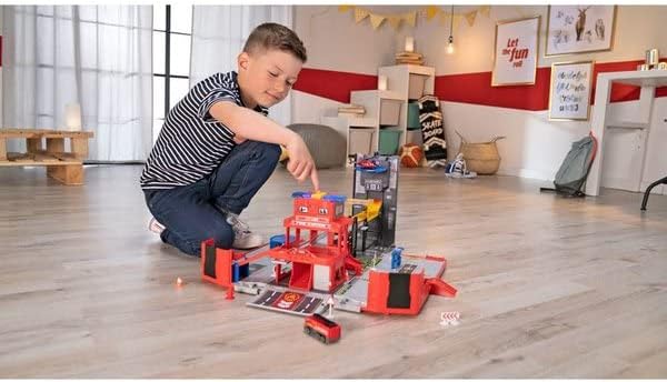 Child playing with the Dickie Toys Folding Fire Truck Playset, moving a small red car down a ramp.