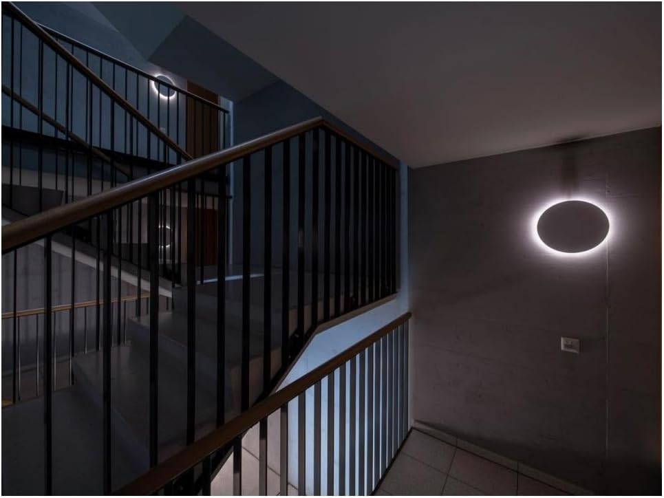 A round Steinel RS PRO R10 basic SC light fixture installed on a wall next to a staircase, illuminated