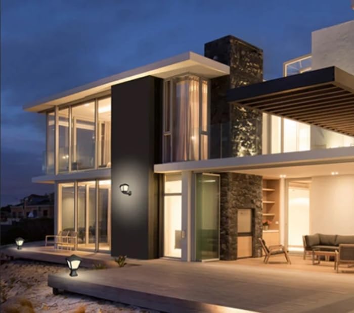 Two Fumagalli Garden Lamps illuminating a modern house exterior at night, one on a wall and another on a low pillar near a patio.