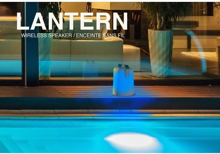 Muvit Lantern speaker glowing blue next to a swimming pool at night.