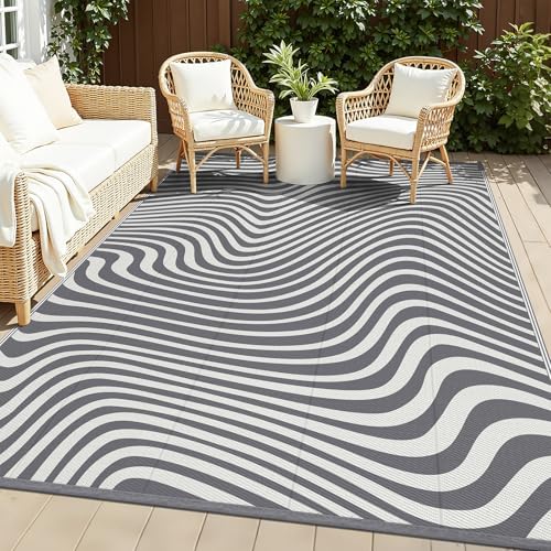 Vaukki grey striped 5x8 outdoor rug staked on a deck — shows the ground stakes that keep a rug flat in wind