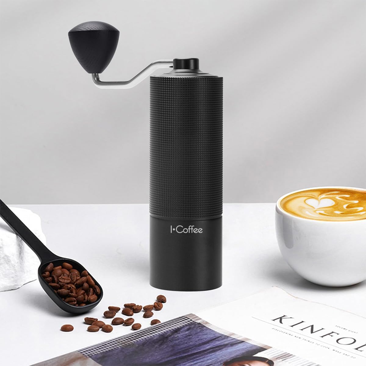 Moedor de café iCoffee C3S posicionado ao lado de uma xícara de café quente e uma colher medidora com grãos.