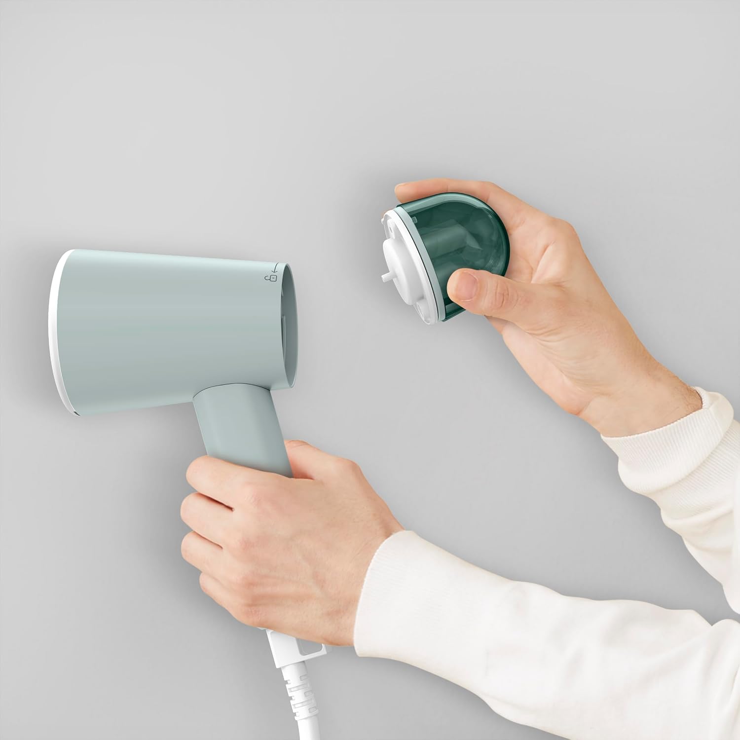 The Tefal Origin Travel DT1034 Garment Steamer, folded, next to a travel bag and other items, highlighting its travel-friendly size.