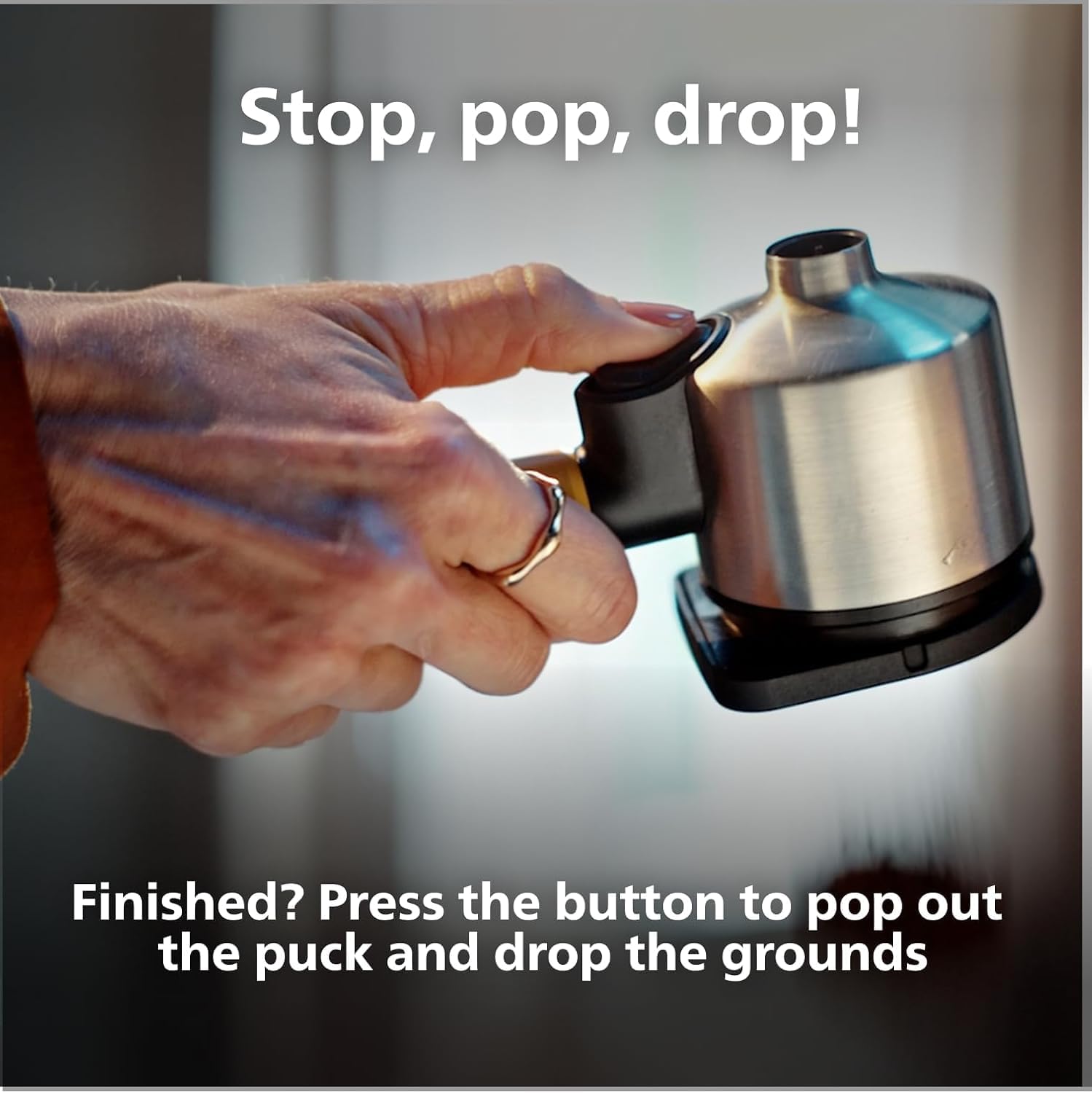 Hand pressing a button to release a used coffee puck from the portafilter.