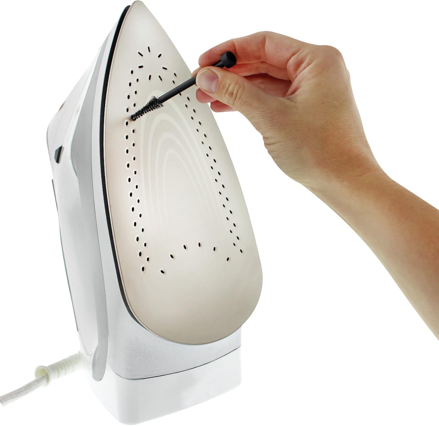 A hand using the small brush to clean the steam holes on an iron's soleplate.