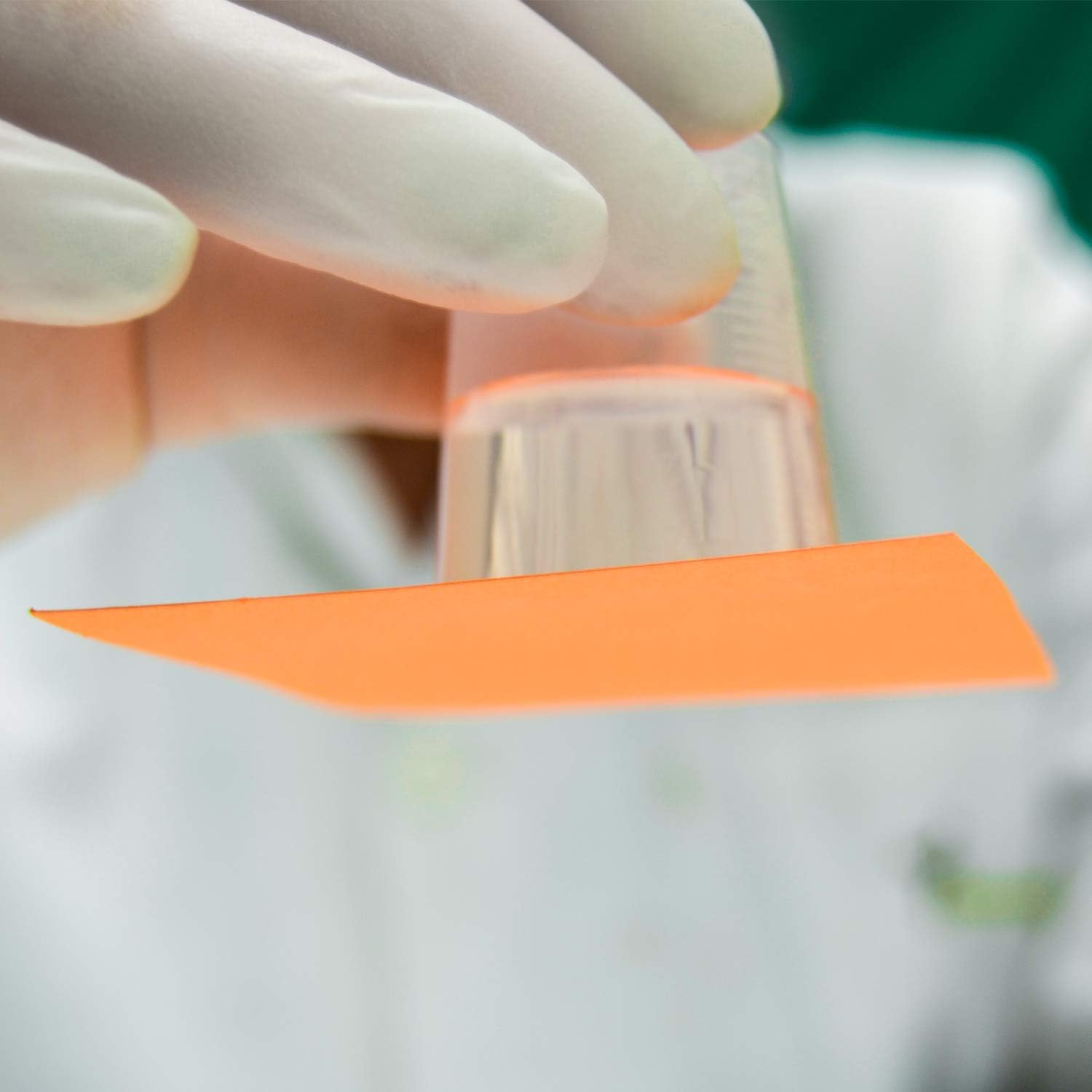 Hands wearing gloves carefully measuring liquid into a small container