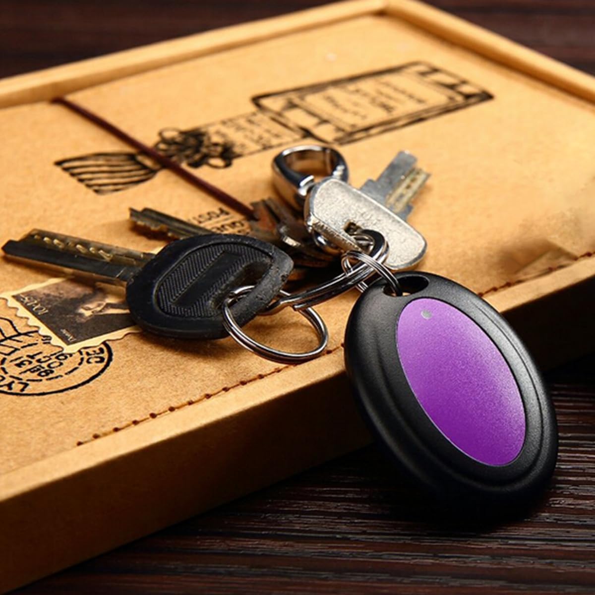 A VODESON key finder receiver, purple in color, attached to a set of house keys on a wooden surface.