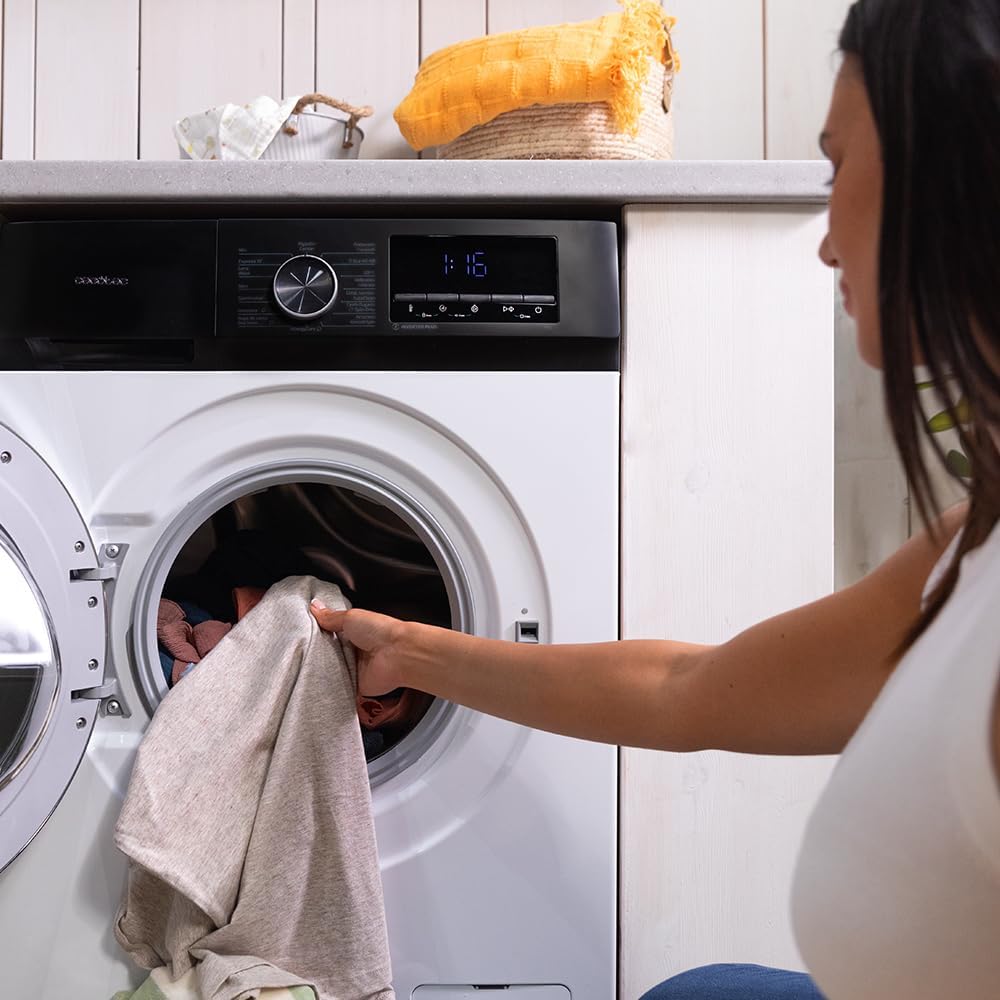 Person loading clothes into the washing machine drum