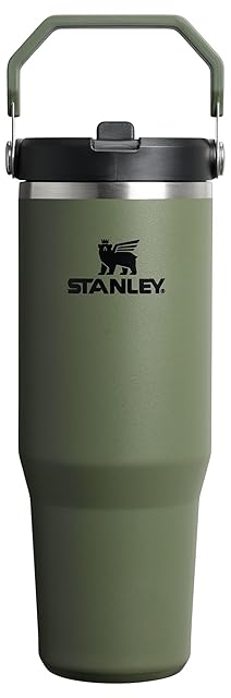 Stanley IceFlow 2.0 Flip Straw Tumbler with Handle 30 oz in dried pine recycled stainless steel finish on a warm wooden gym bench, the twist-on lid with flip-up straw visible, the 2026 successor to the viral Stanley Quencher with the leak-resistant fix that solves the original removable-straw problem