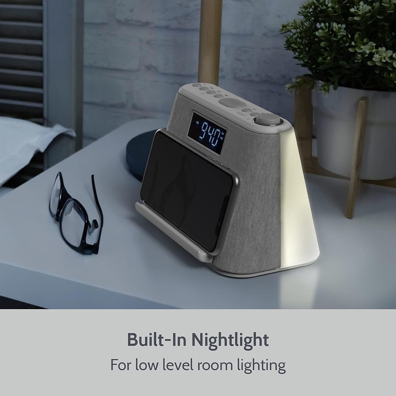 i-box alarm clock radio on a bedside table with its nightlight illuminated, providing soft room lighting.