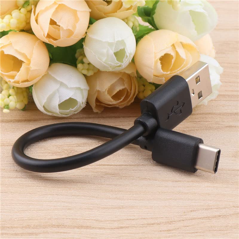Short black USB to Type-C cable on a wooden surface with flowers