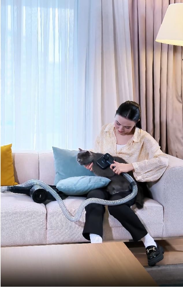 A woman using the pet grooming attachment on a cat, connected to the Sinbo SVC-8623 vacuum cleaner.