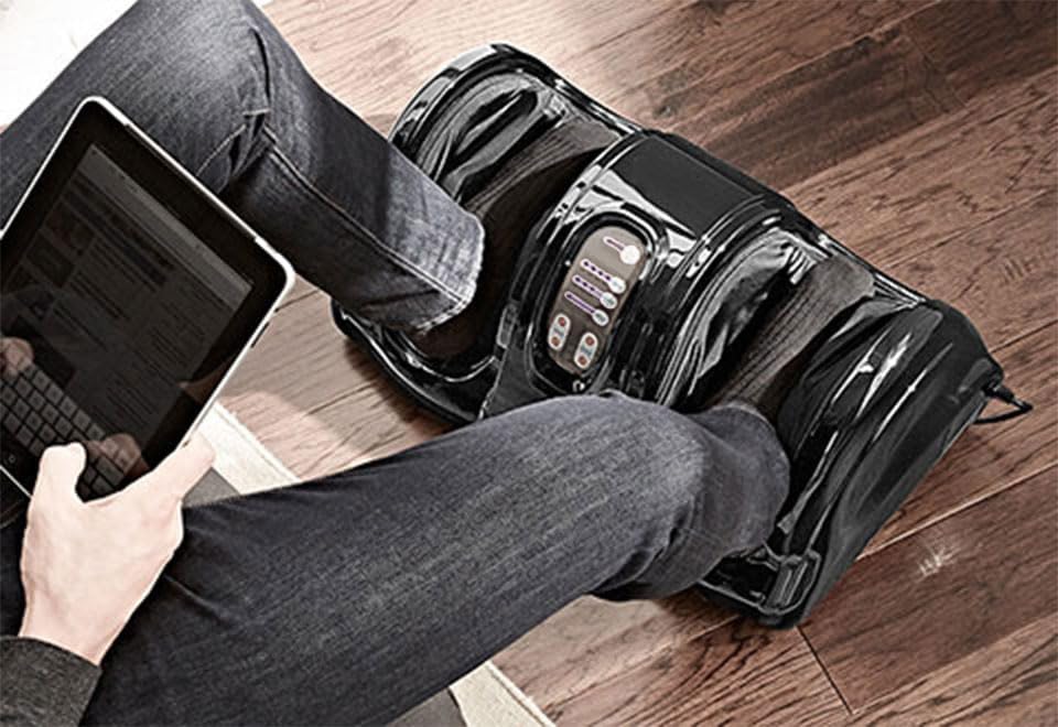Person using the Sharper Image Foot Massager while relaxing with a tablet