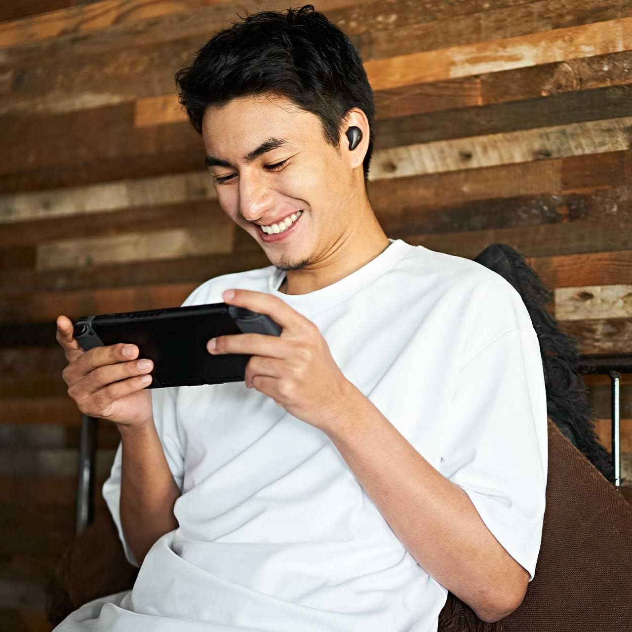 User wearing radius HP-P100BT earphones while playing a portable game console