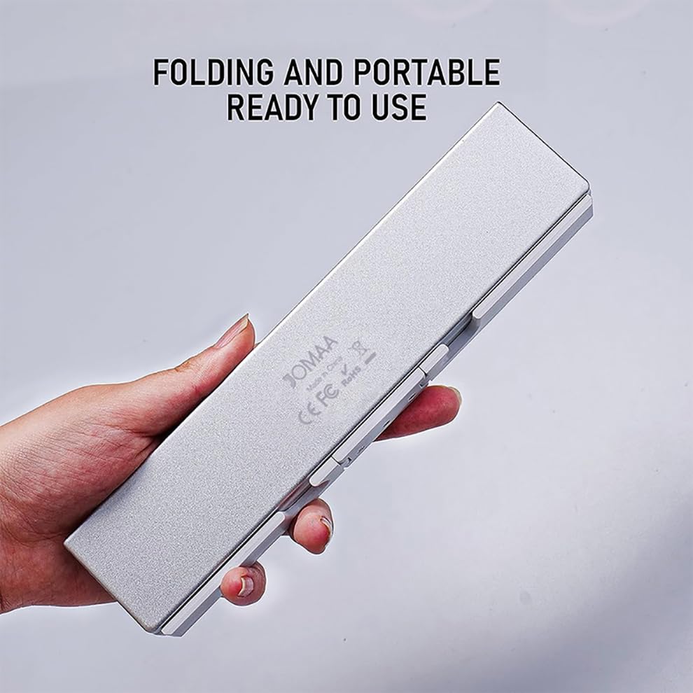 Hand holding the JOMAA Mini Foldable Bluetooth Keyboard in its folded, compact state.