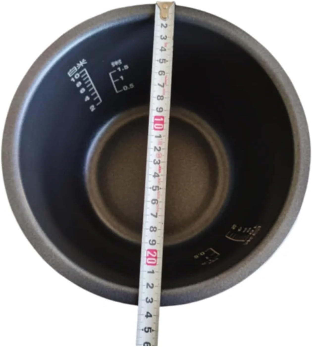 Top-down view of the rice cooker inner pot with a measuring tape showing its diameter, approximately 24 cm.
