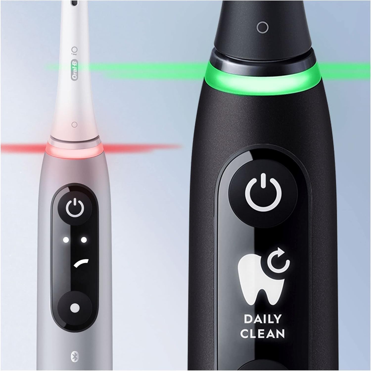 Two Oral-B iO toothbrushes, one showing a red light (excessive pressure) and the other a green light (correct pressure) from the smart pressure sensor.