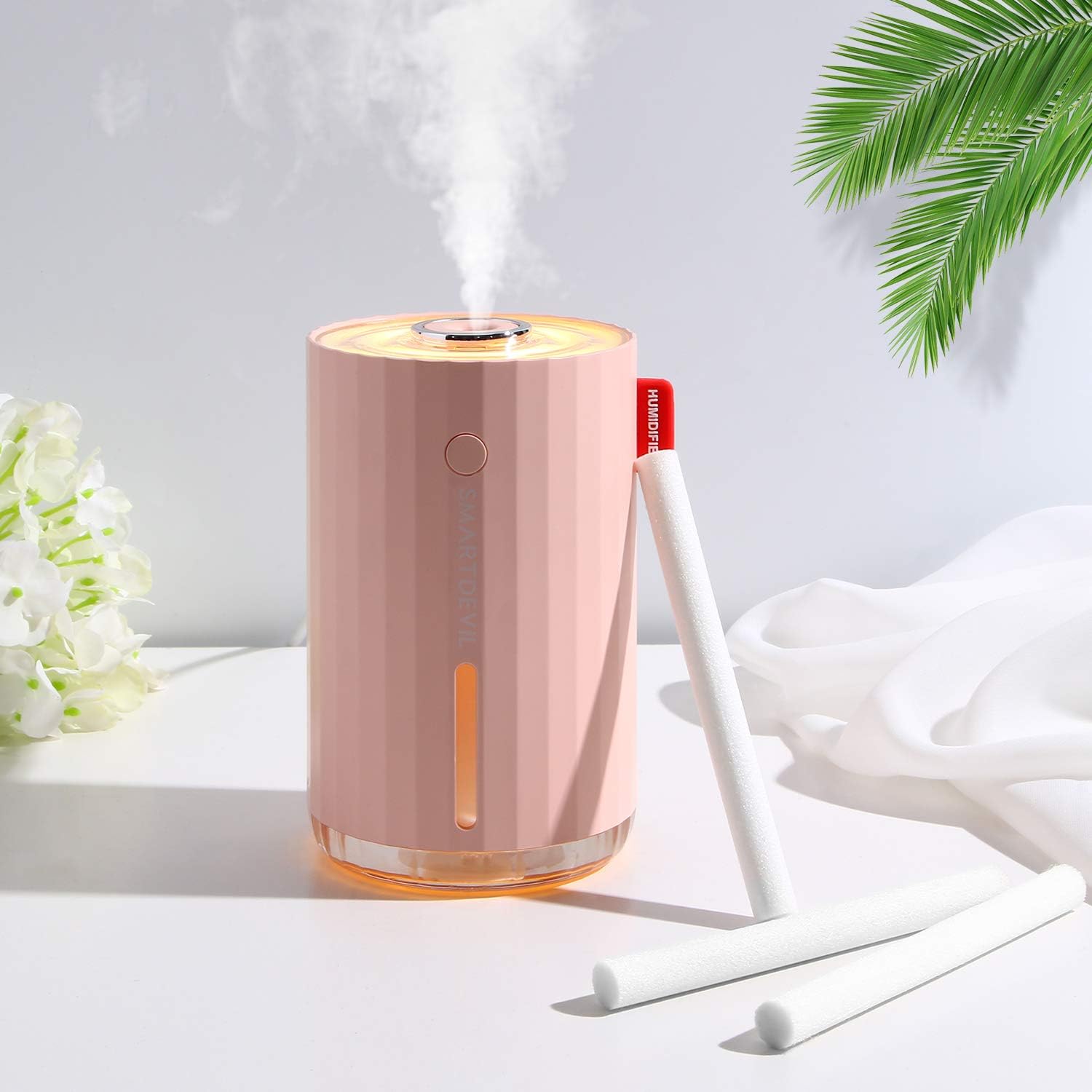 A pink portable humidifier with filter sticks next to it.