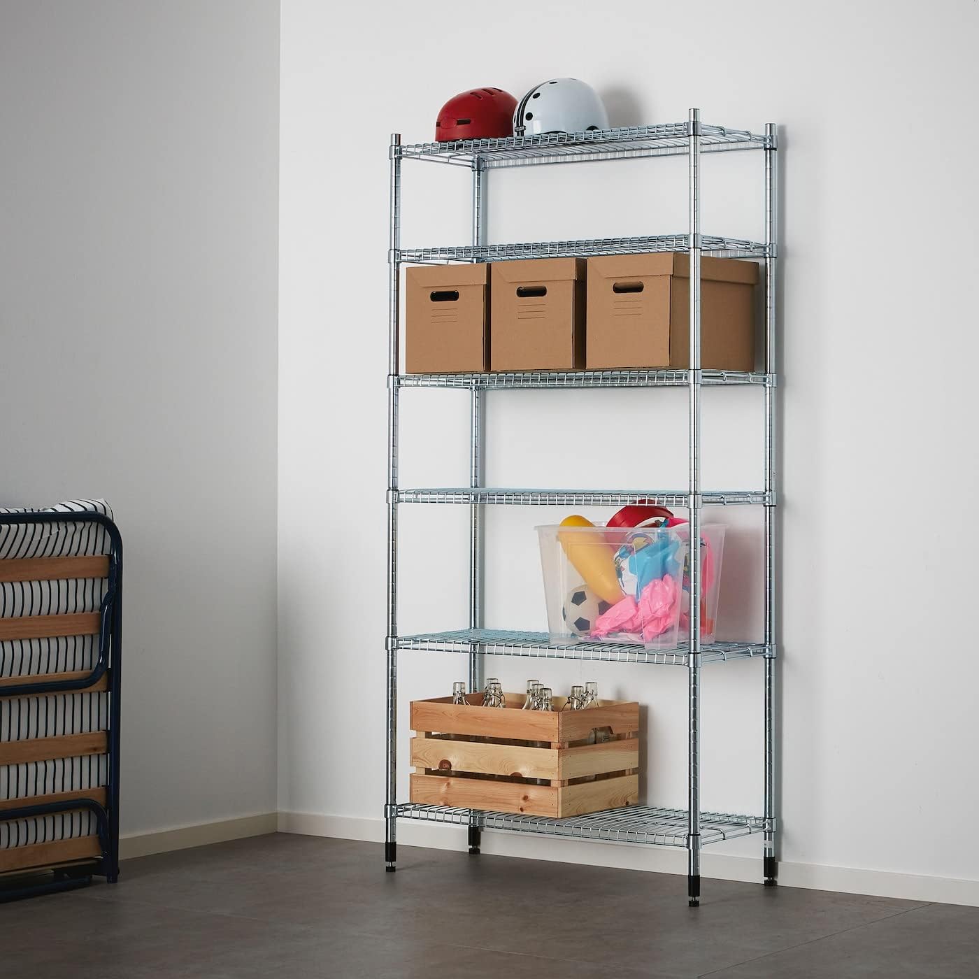 IKEA OMAR shelving unit in a room, holding various items like cardboard boxes, a clear storage bin with toys, and a wooden crate with bottles.