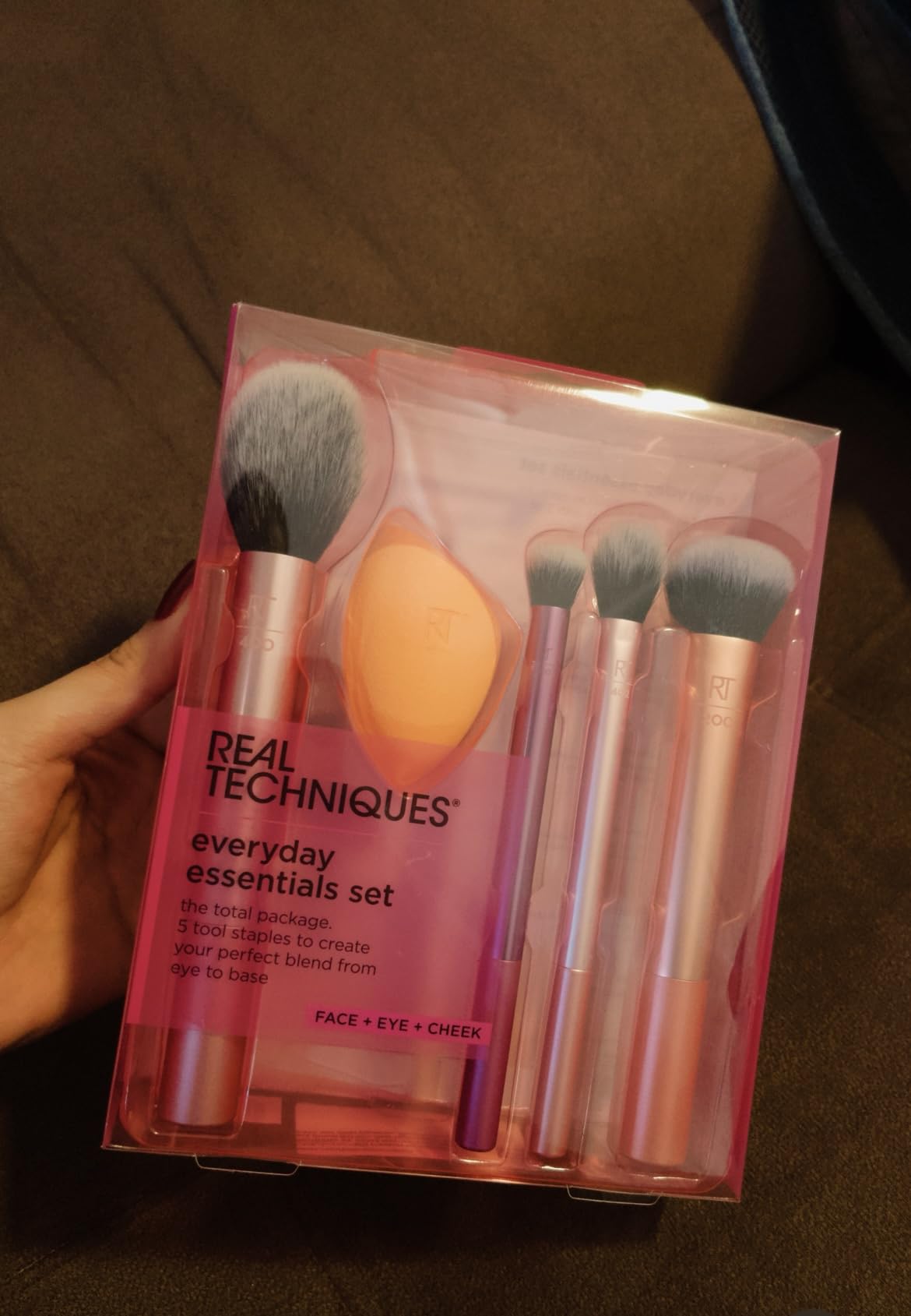 Mão segurando a embalagem fechada do kit Real Techniques Everyday Essentials