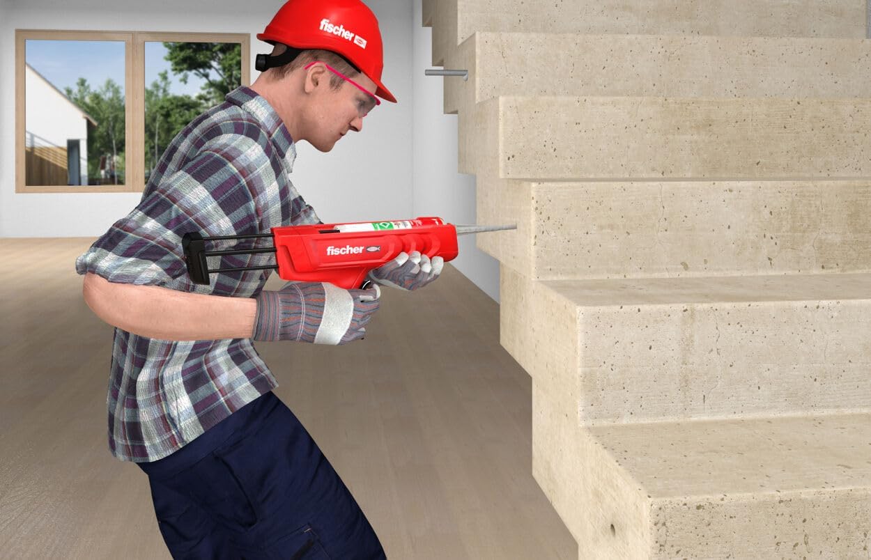 Worker using the Fischer manual dispenser to inject chemical mortar into a borehole on a vertical concrete surface