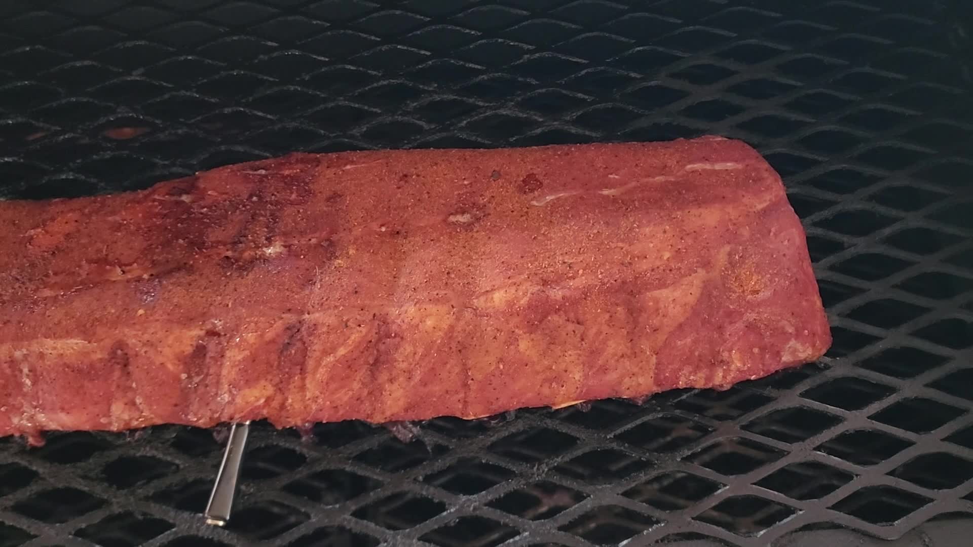 A large cut of meat cooking on a grill, with an inset showing the Inkbird thermometer probe charging in its case, indicating fast charging capabilities.