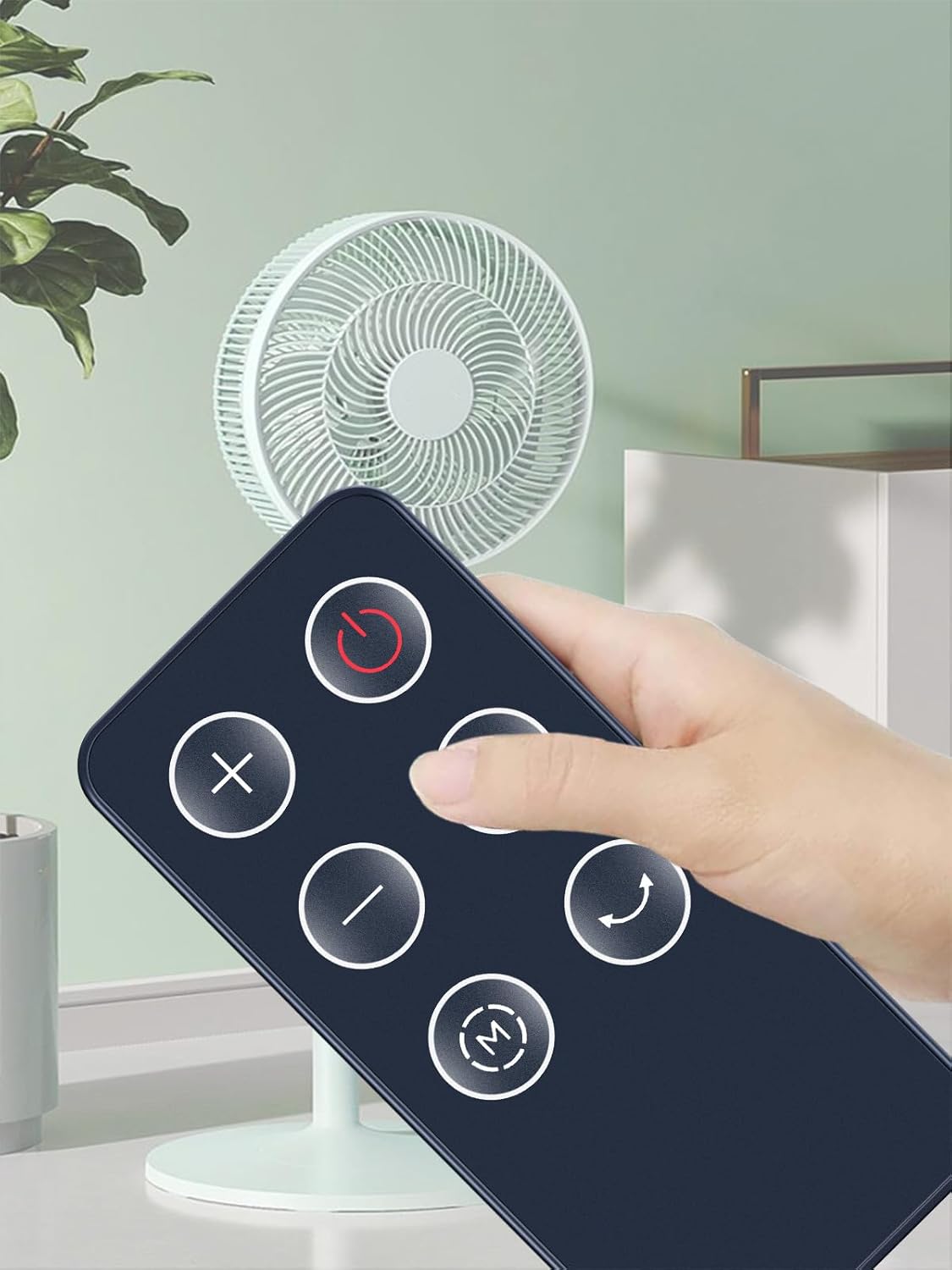 Hand holding the remote control, pointing towards a fan