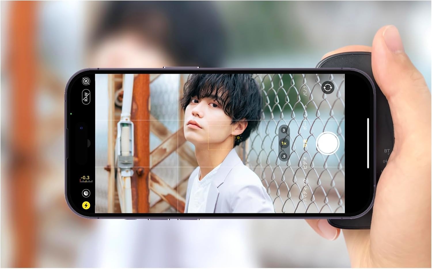 Smartphone attached to Snap CAM, showing camera interface and hand holding the grip