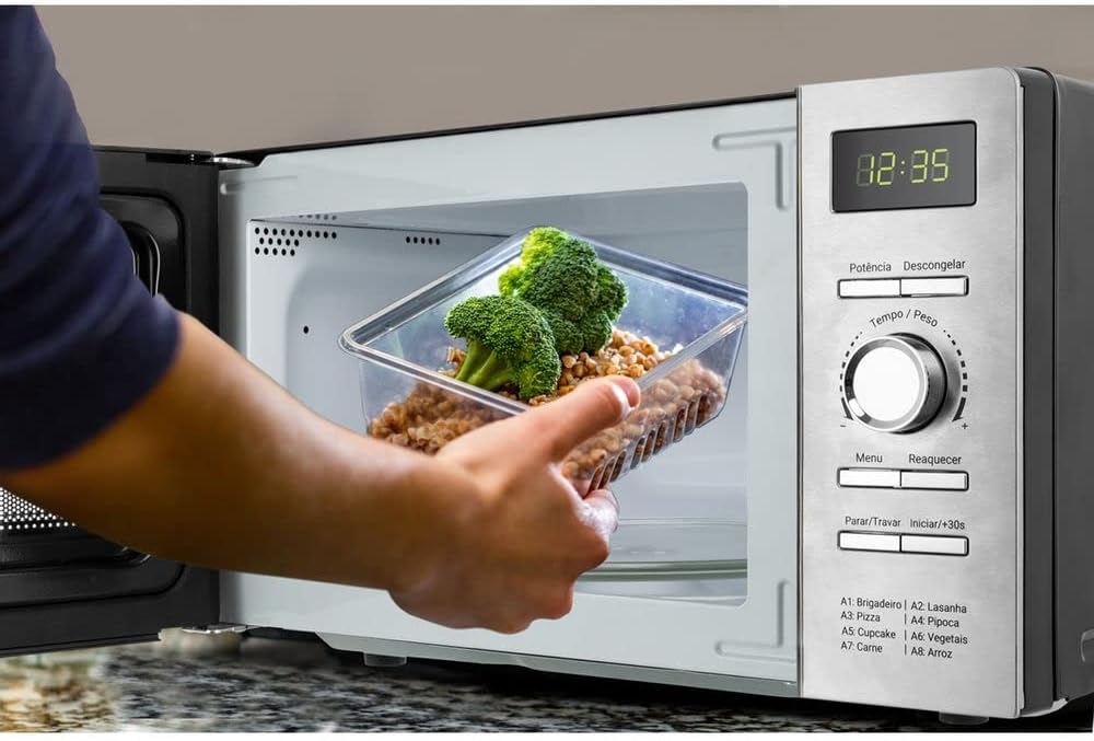 Hand placing a container of food into the microwave oven