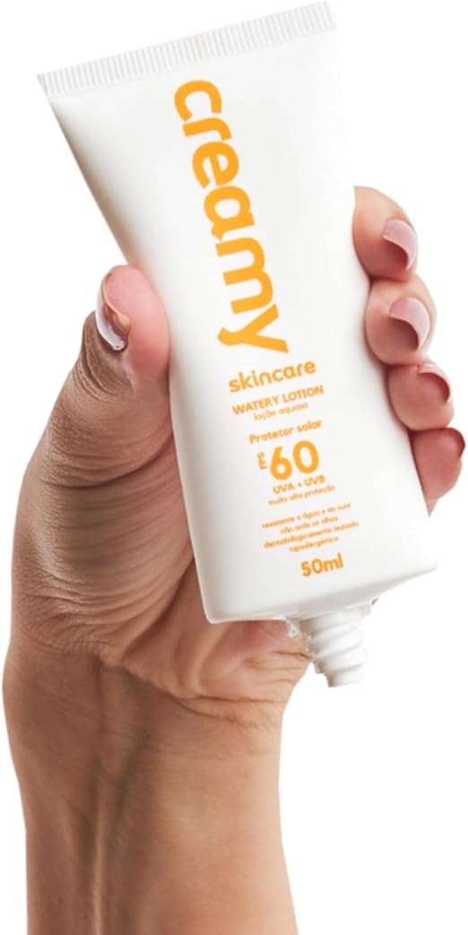 Mão segurando o tubo do protetor solar Creamy posicionado para aplicação