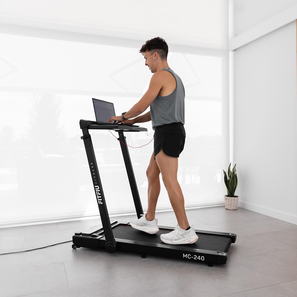 A person walking on the treadmill while working on a laptop placed on the integrated PC support.