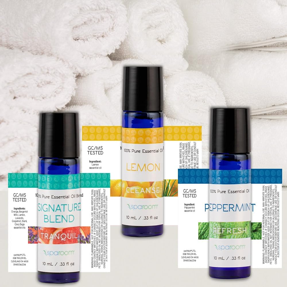 Close-up of three SpaRoom essential oil bottles: Signature Blend, Lemon, and Peppermint, showing their labels and ingredients.