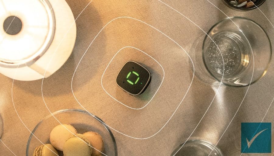 Overhead view of the Wi dex Sound Assist device placed on a table surrounded by various items, with concentric circles emanating from it, symbolizing sound capture.