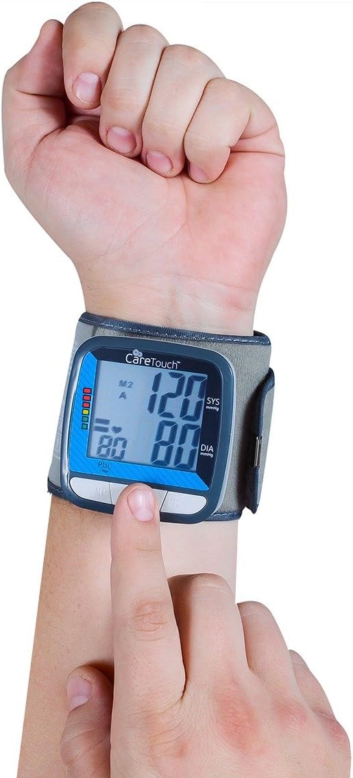Person wearing Care Touch wrist blood pressure monitor on their left wrist, with the display facing up, and pressing the start button.