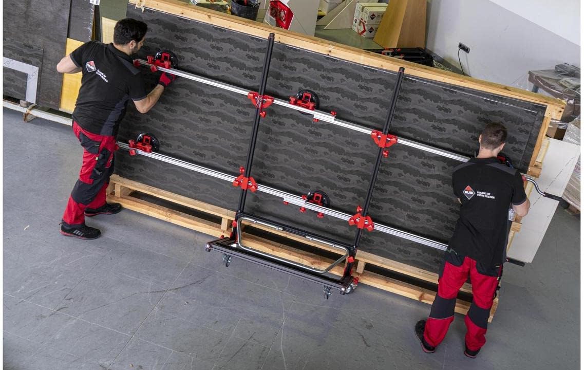 Two workers preparing to lift or set down a large dark-colored slab horizontally, with the RUBI Slim Easy Trans Plus attached, showing the tool's full length.