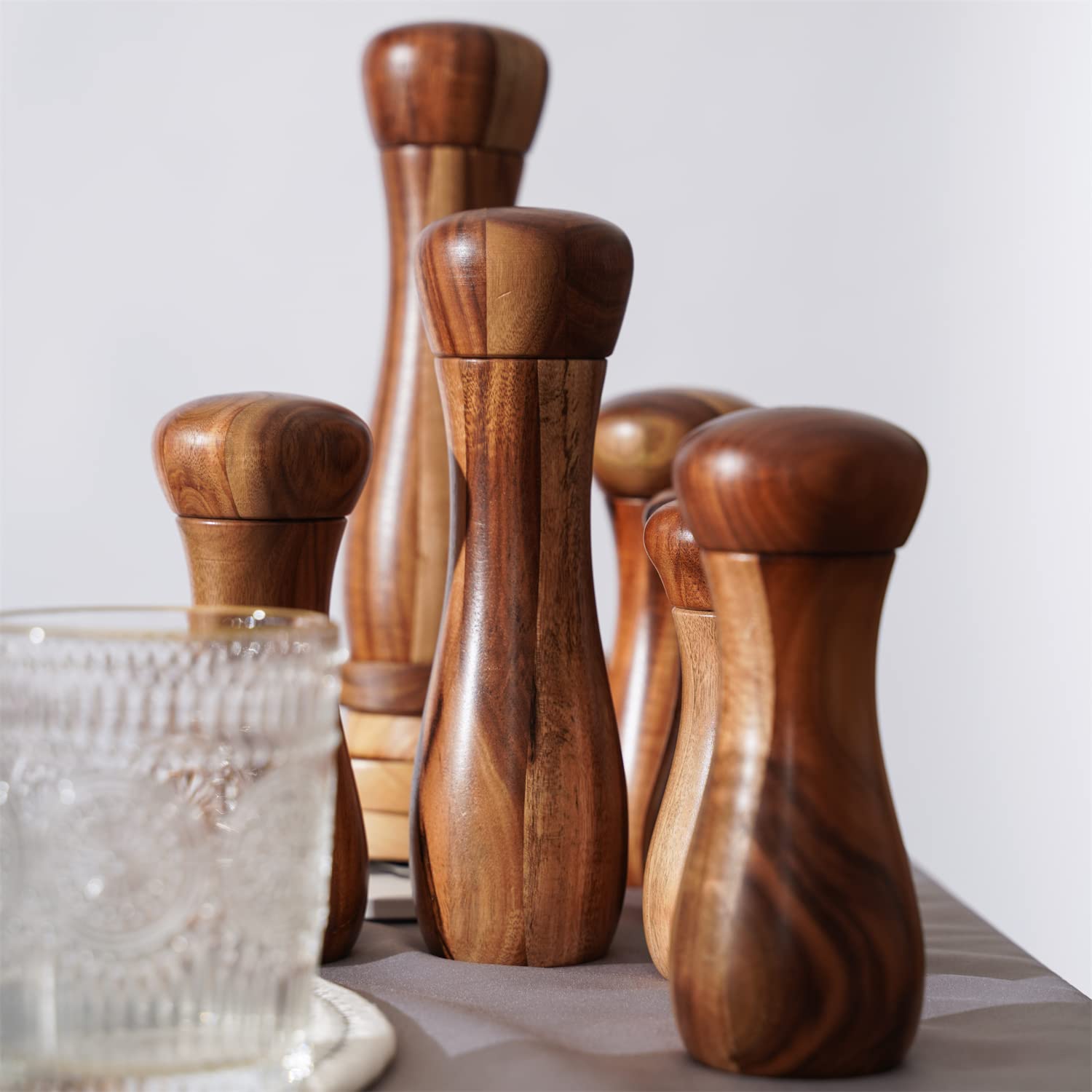 Zestaw młynków do soli i pieprzu DeroTeno wraz z podstawką. Dwa młynki do soli i pieprzu z ceramicznym mechanizmem mielenia. Drewno akacjowe, wysokość 20,5 cm, średnica 6 cm.