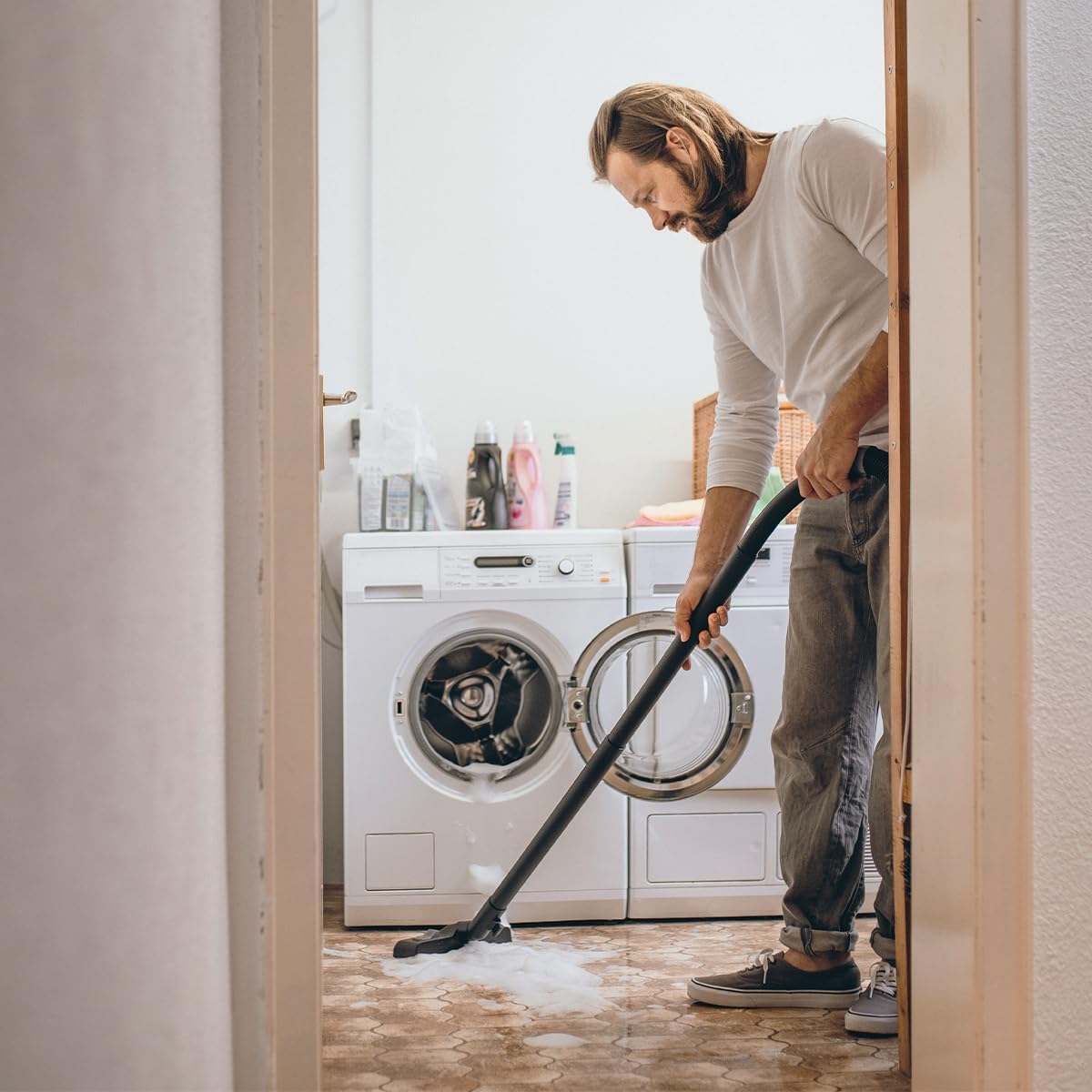 Man vacuuming wet floor in a laundry room with Kärcher WD 5 V-25/5/22