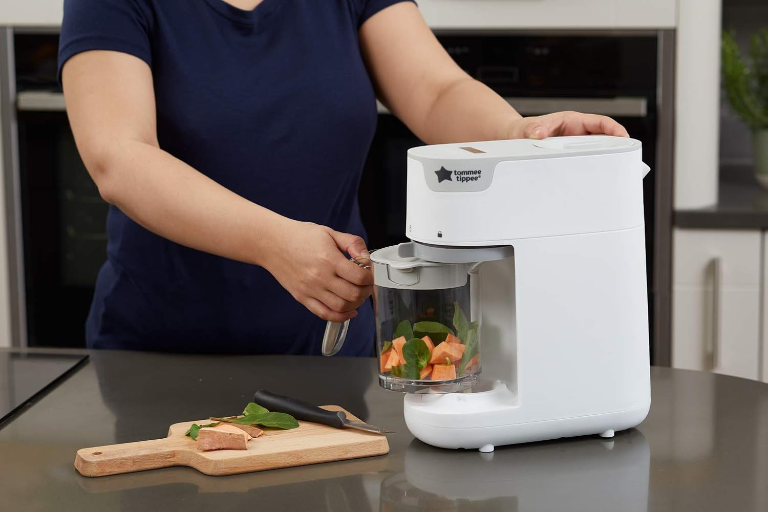 A person placing the blending jug with ingredients into the Tommee Tippee Quick Cook Baby Food Maker.