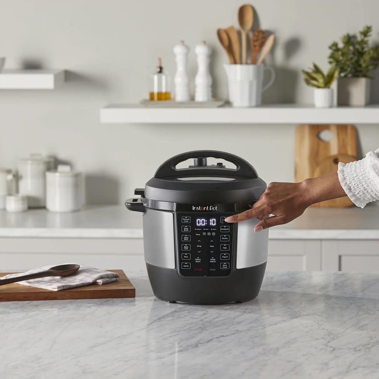 A hand pressing a button on the Instant-Pot RIO control panel