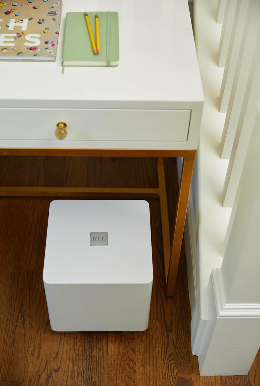 REL T/5x Powered Subwoofer placed next to a desk in a room