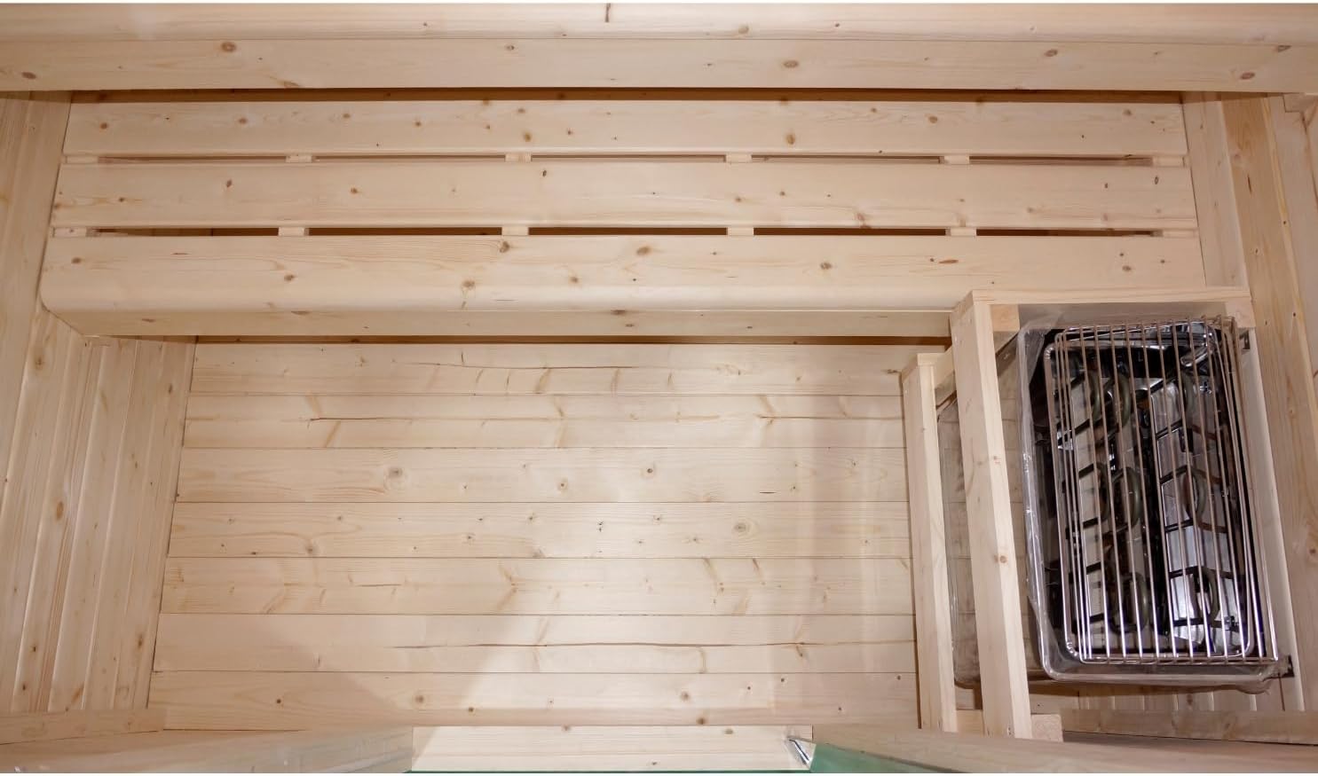 Interior view of the sauna showing the heater unit and the upper wooden bench.