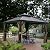 Kozyard Alexander 12' x 12' Hardtop Gazebo, Aluminum Frame with Galvanized Steel Double Roof, Outdoor Permanent Pavilion with Curtains and Netting for Patio, Backyard, Deck, Lawn(Brown)