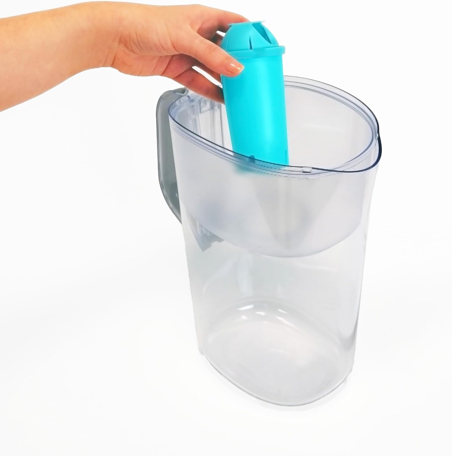 A hand pouring dark filter granules from a sachet labeled 'ALKALINE' into a blue Phox filter cartridge. Oranges and lemons are scattered around on a blue surface.