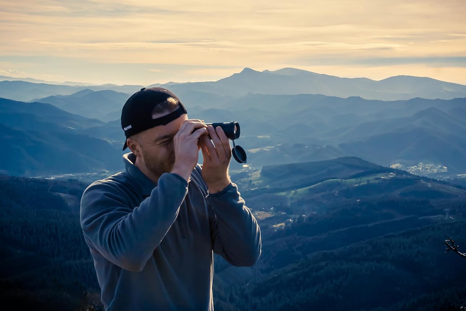 A person using the Opticron Explorer WA ED-R 10x42 Monocular outdoors, looking at a distant landscape.