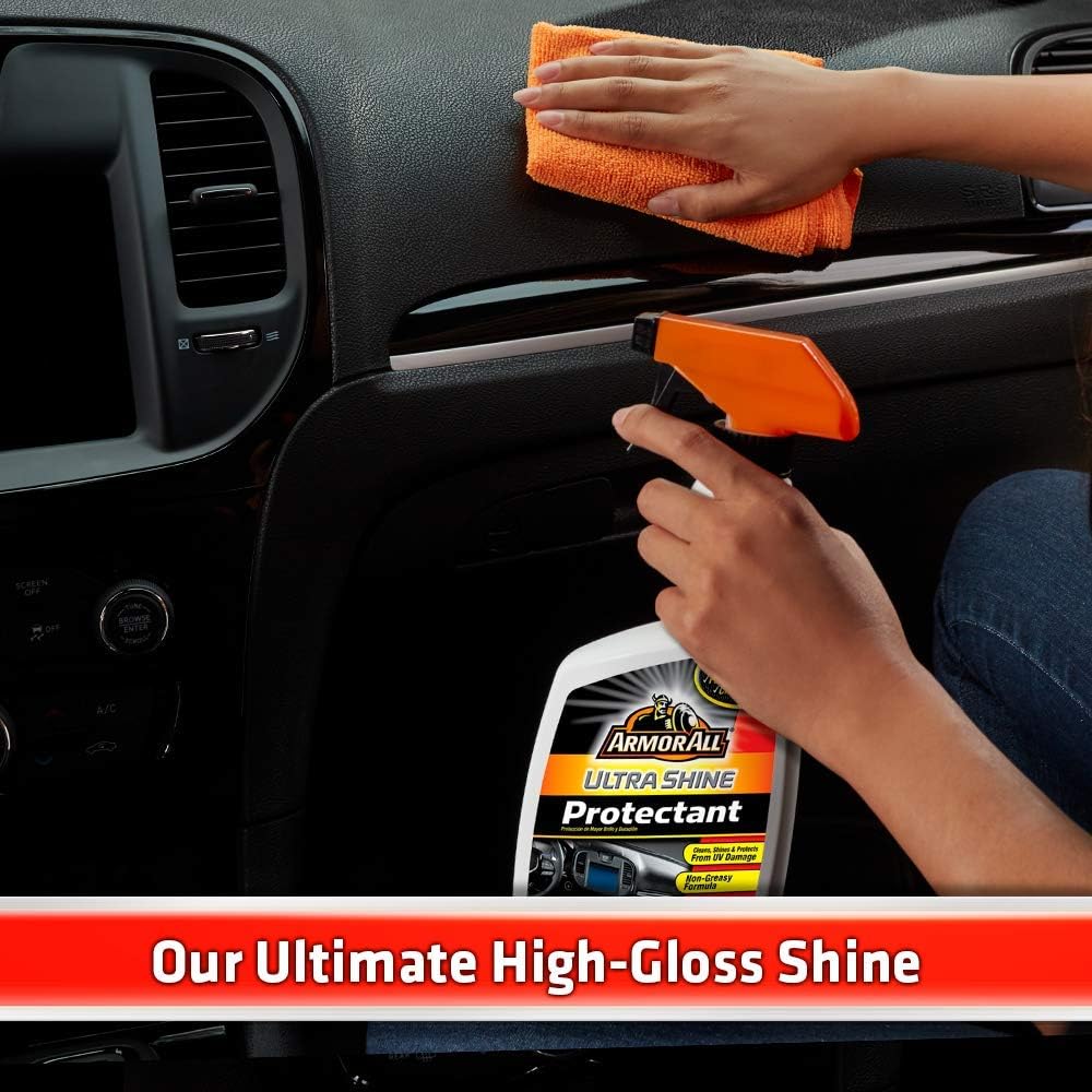 Hand applying Armor All Ultra Shine Protectant to a car dashboard with a microfiber cloth