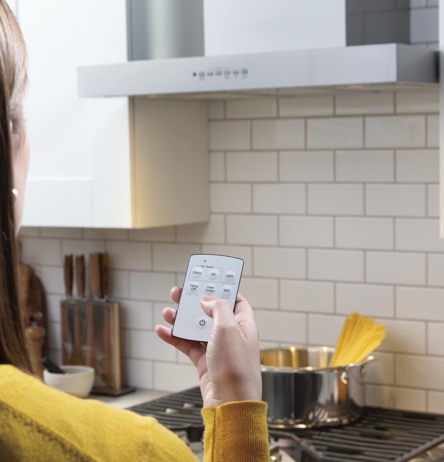 Hand holding the remote control for the range hood