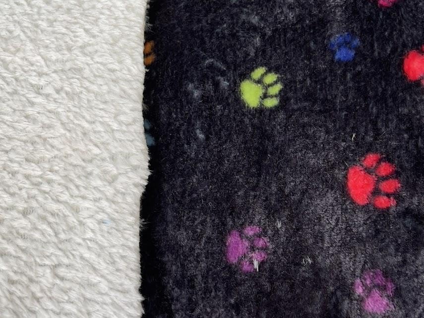 Superweicher Fleece-Stoff, kleine Pfoten auf schwarzem Muster