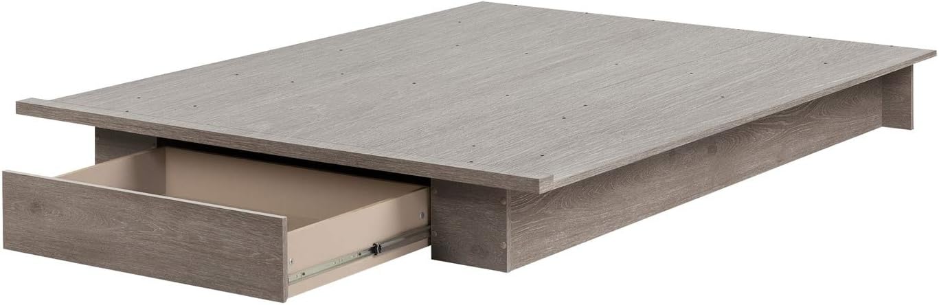 A South Shore platform bed in a lighter wood finish, demonstrating the functionality of the under-bed storage drawer.